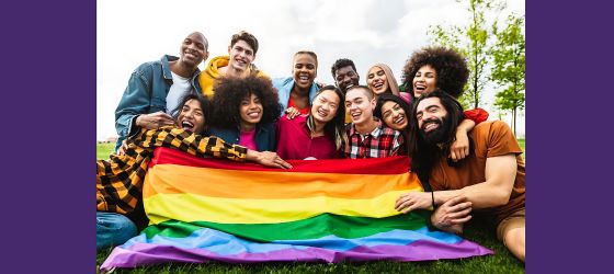 A smiling group of people pose with a Pride flag